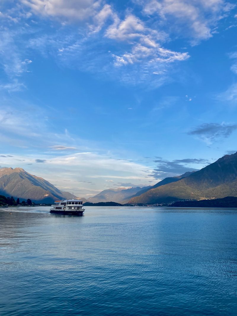 A passenger ferry crossing the lake at dusk, with the Alto Lario mountains behind