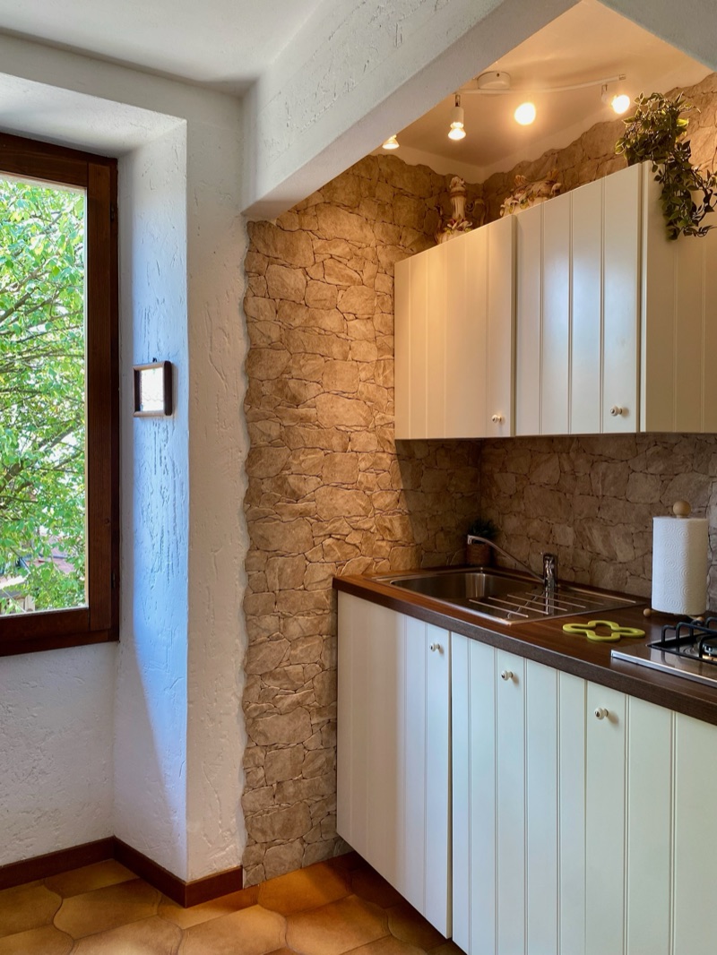 The kitchenette of Ciclamino set against the exposed stone wall, beside a bright window