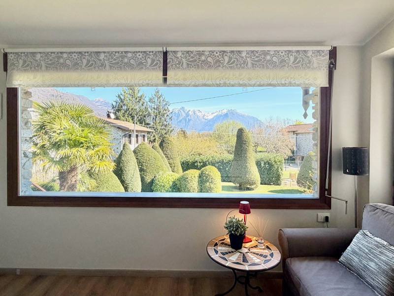 Panorama's picture window framing the garden's sculpted trees and the snow-dusted mountains