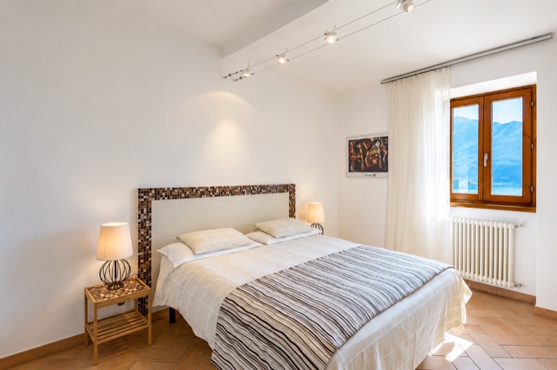 Dalì's main bedroom with a striped bedspread, mosaic headboard and mountain light from the window