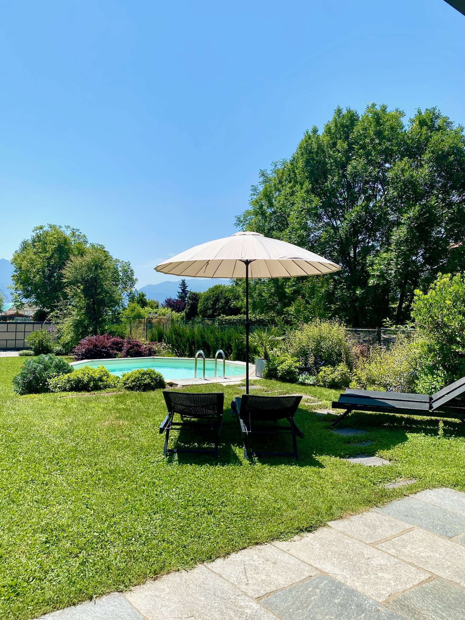 A parasol and two loungers on Villa Larius' lawn beside the saltwater pool