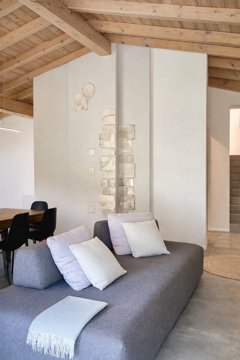 A deep grey daybed piled with white cushions in a corner of the living space