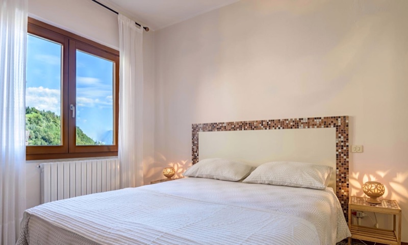 The main bedroom of Picasso with a mosaic headboard and a window onto the green hillside