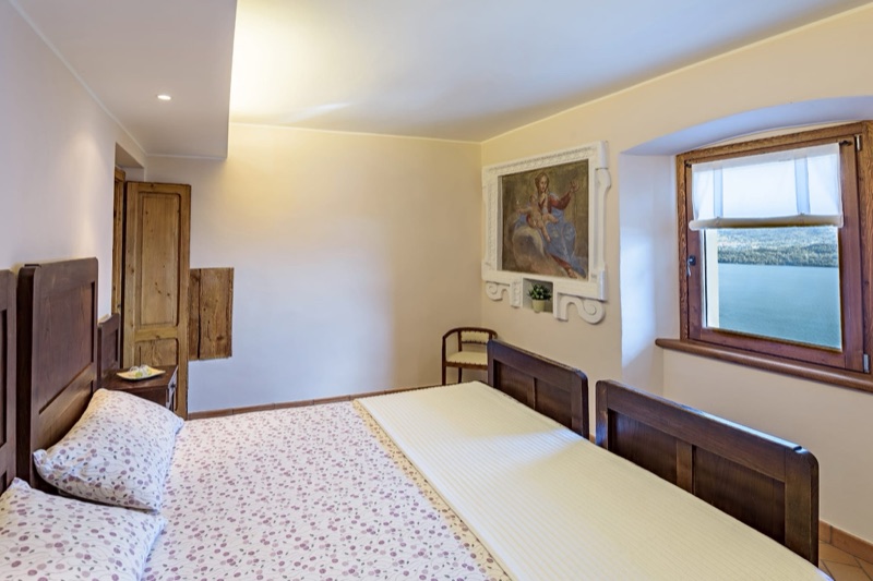 A bedroom in Sole Luna with wooden beds and a deep window looking onto the lake